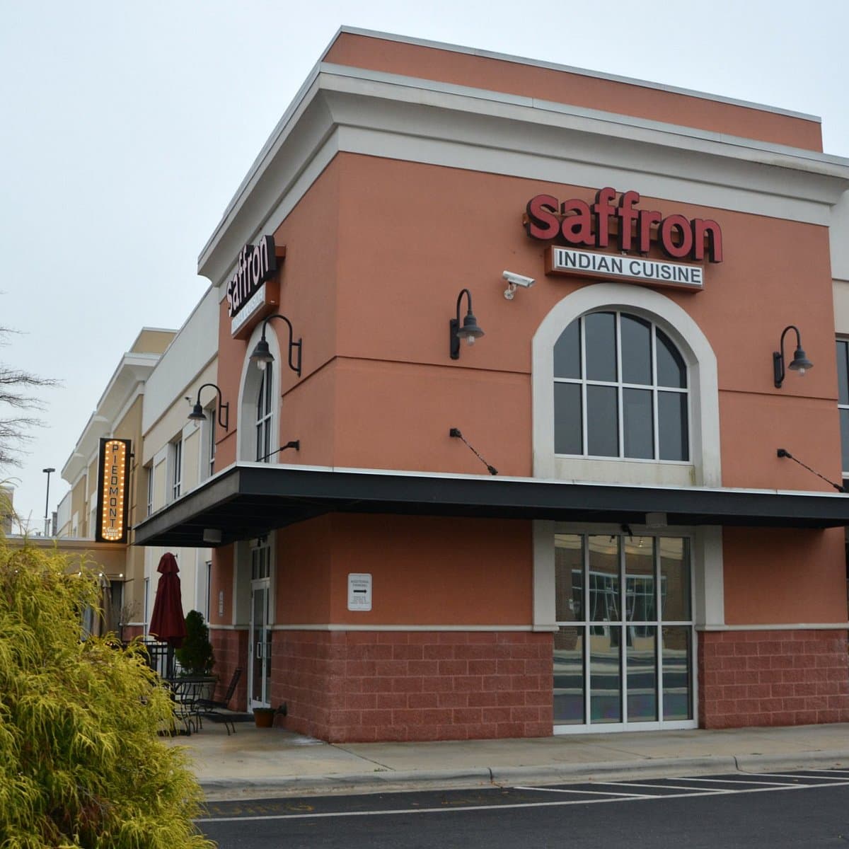 Saffron Indian Cuisine's corner storefront in Charlotte: terracotta walls, arched windows, and the red saffron sign over the door.